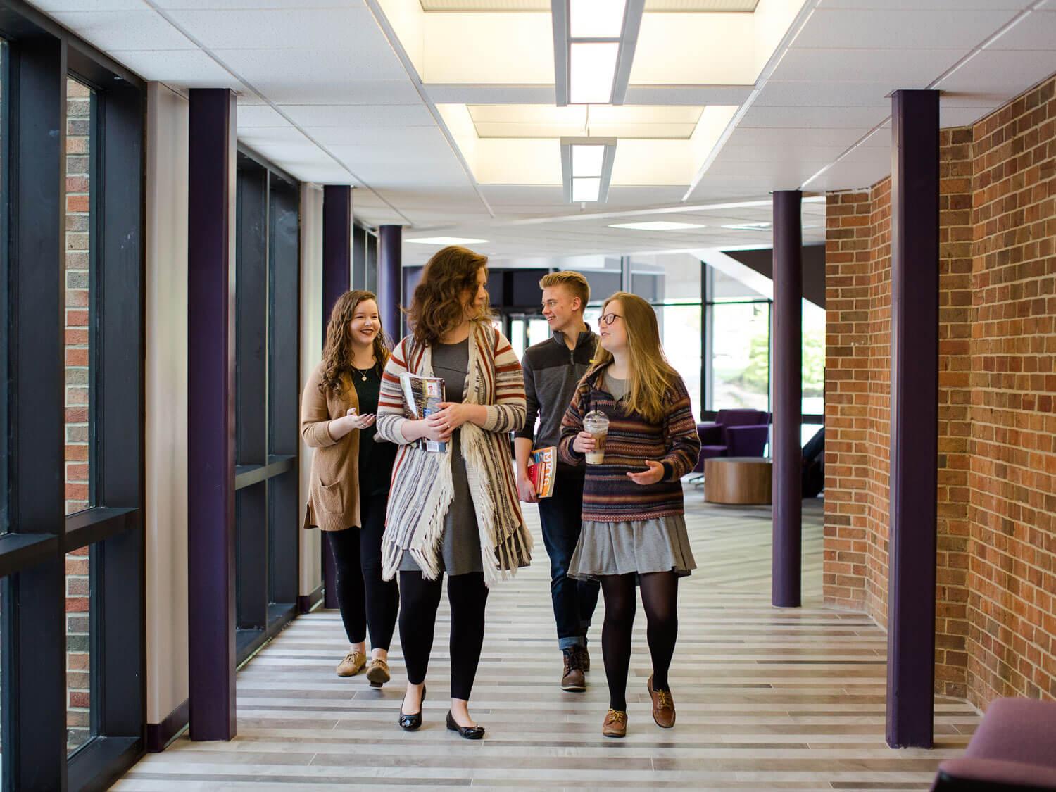Professor and students walk down hallway in conversation