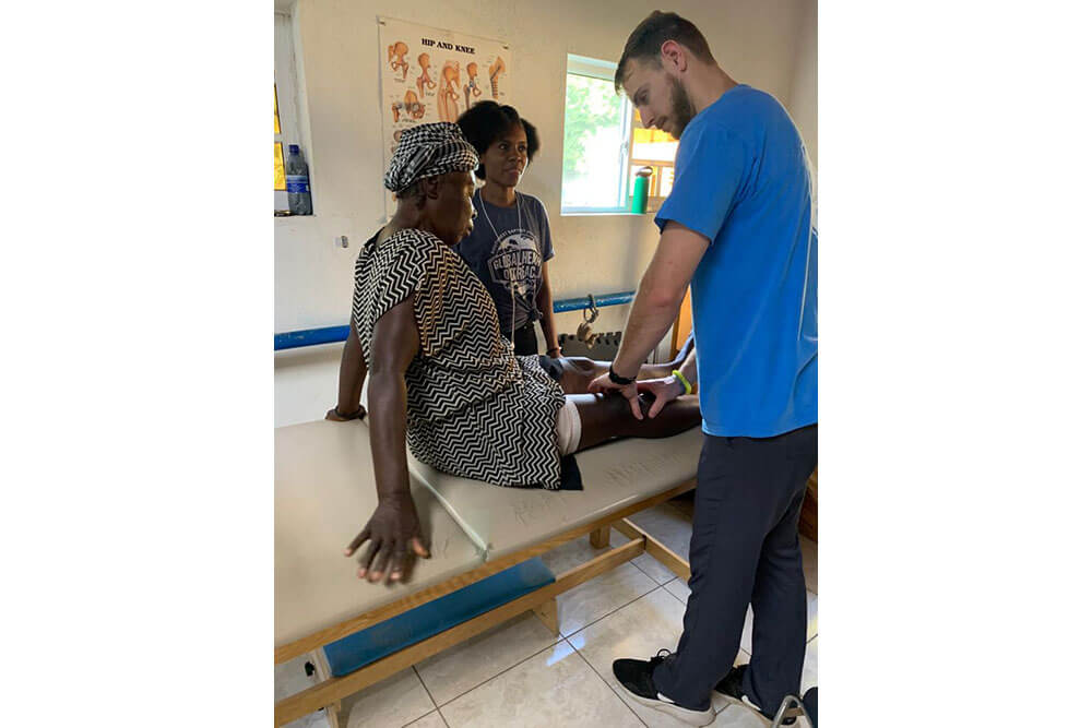 SBU Physical Therapy student examines patient's leg in Haiti