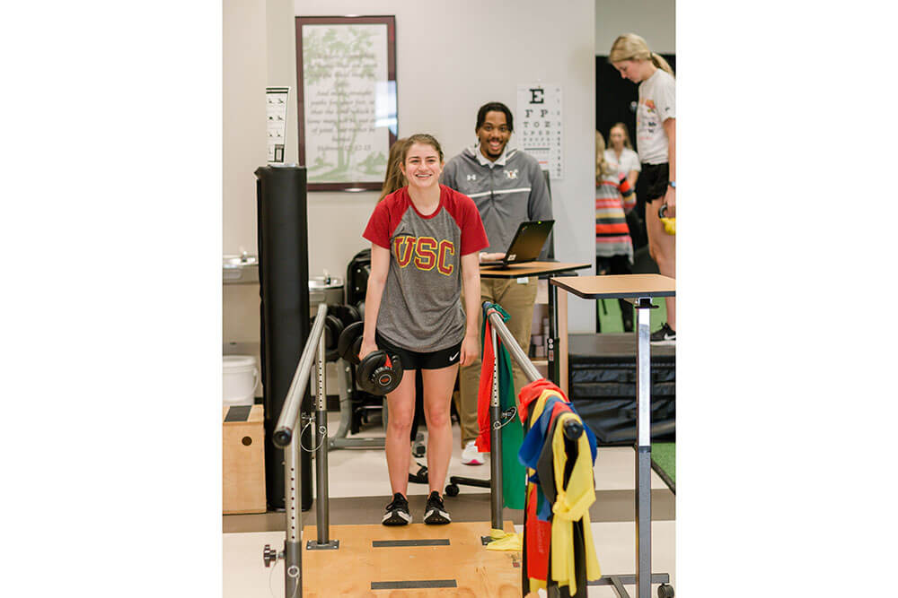female patient walks between guardrails