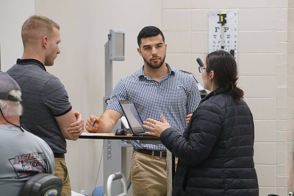 Physical therapy students in discussion around laptop