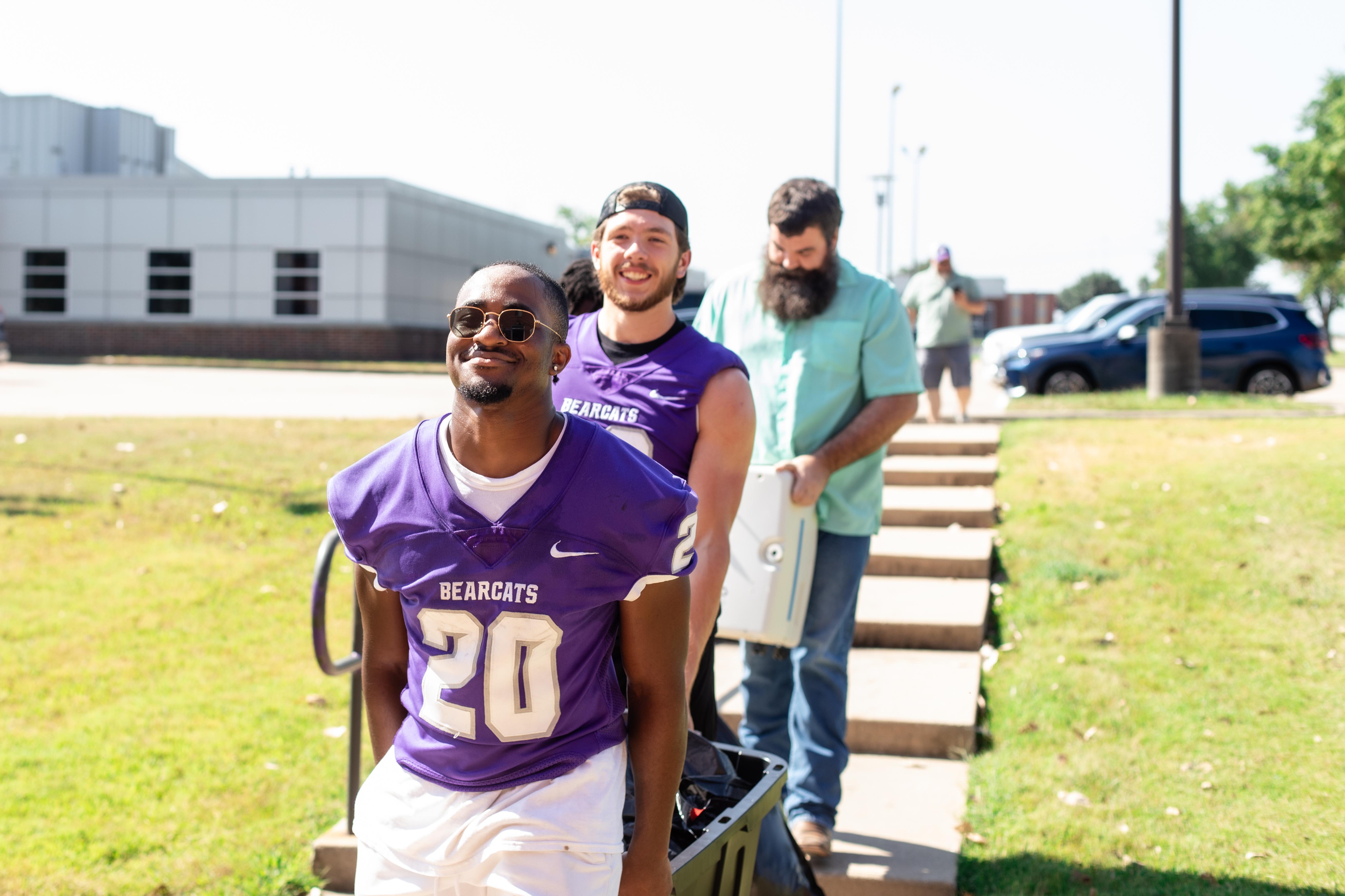 Football players helping carry furniture to the dorm during Welcome Week 2024.