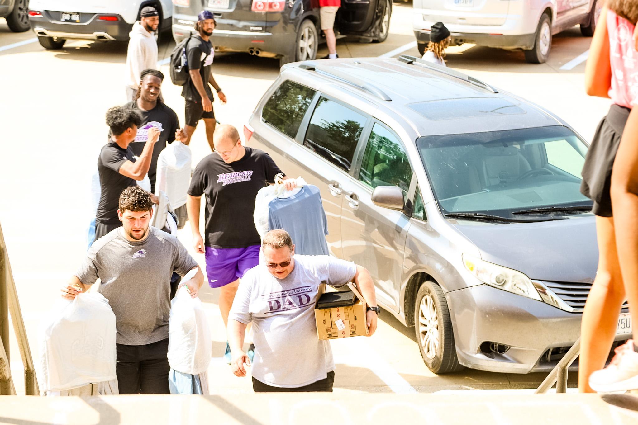 Football players helping carry furniture to the dorm during Welcome Week 2024.