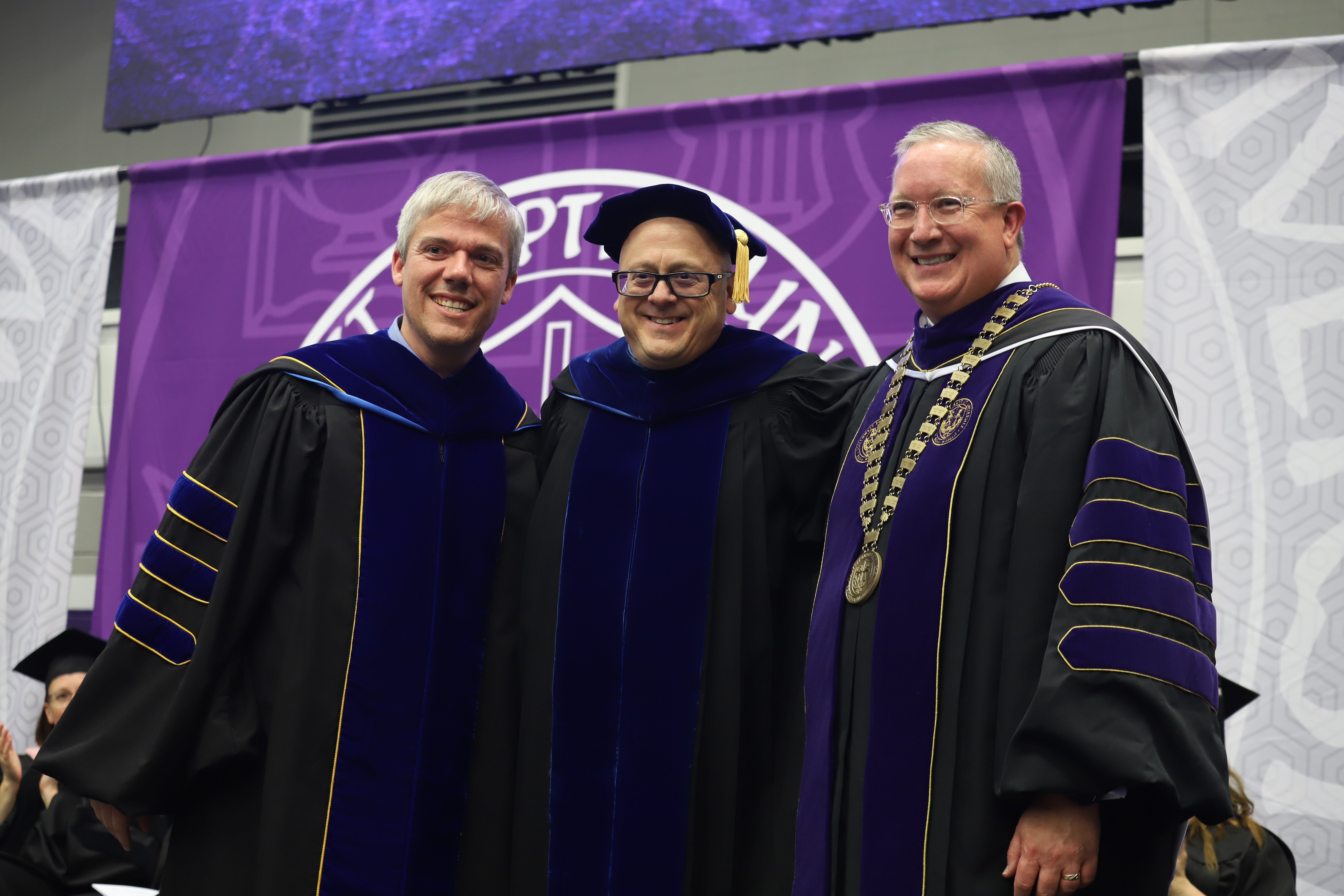 Provost Lee Skinkle, Dr. Duke Jones, and President Rick Melson pose for picture while wearing graduation regalia