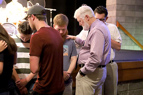 SBU students, staff and faculty pray over mission team members.