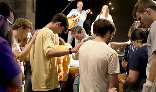 SBU students, staff and faculty pray over mission team members.