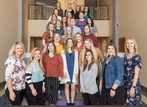nursing students and faculty pose for group photo on staircase
