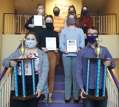 Debate team members holding trophies