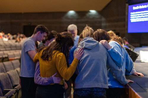 SBU students, staff and faculty pray in a circle praying for each other