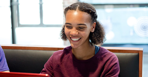 Student smiling while using laptop