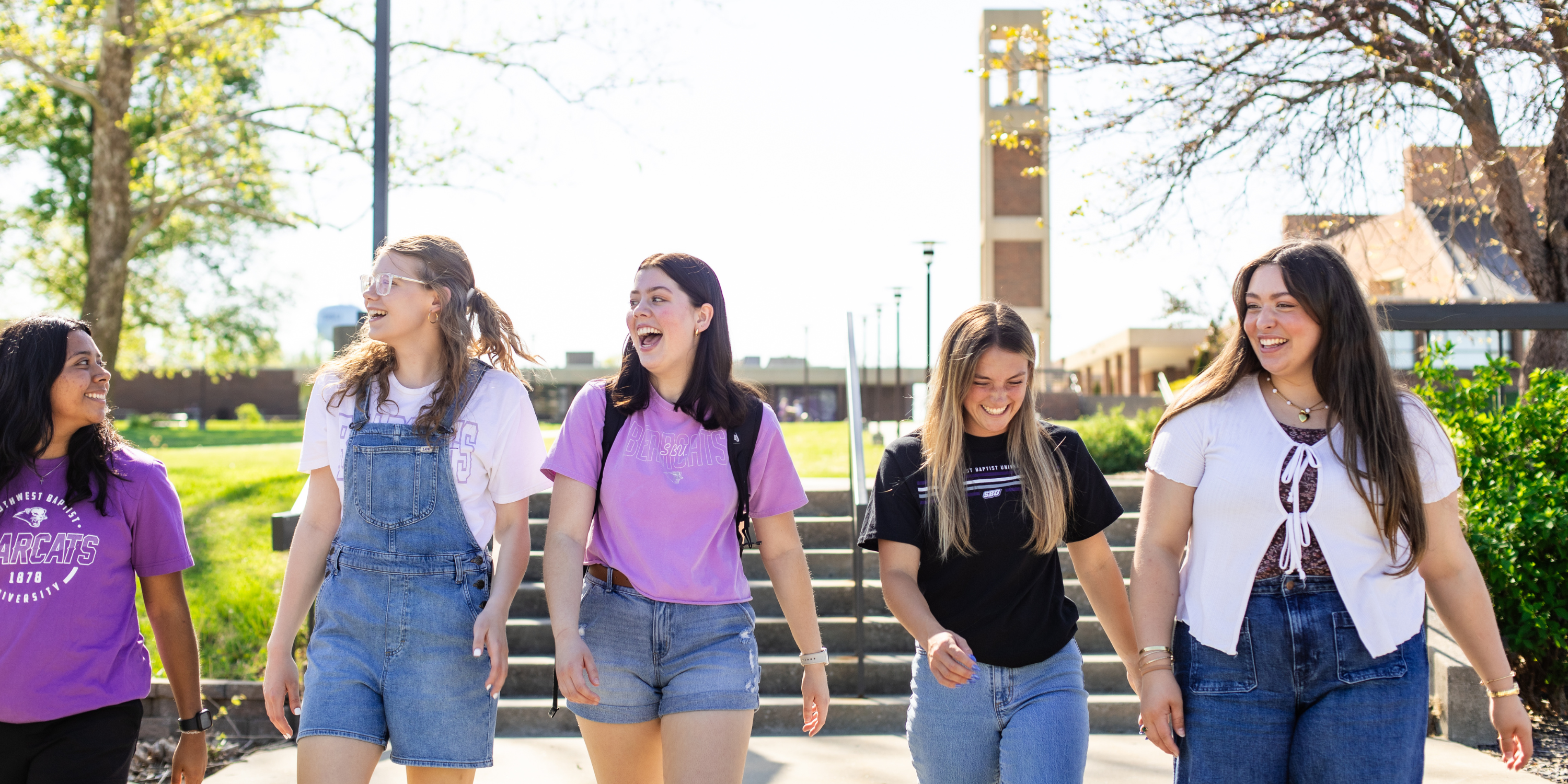 students smiling with bell tower in background