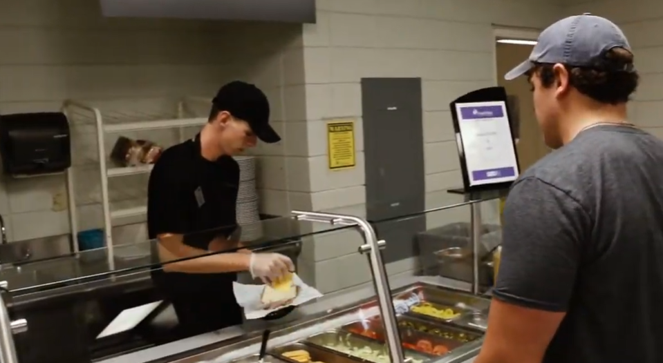 male student waits in line for sandwich at cafeteria
