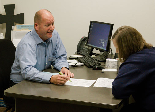professor talks to student sitting at desk