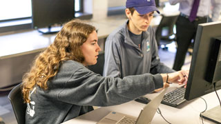 students looking at laptop screens while sitting around conference table