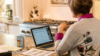 Teacher sitting at kitchen table with laptop
