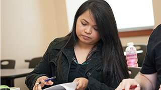Asian girl flipping papers as she sits in class