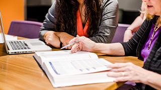 accounting professor looks at computer with student to help her with homework assignment