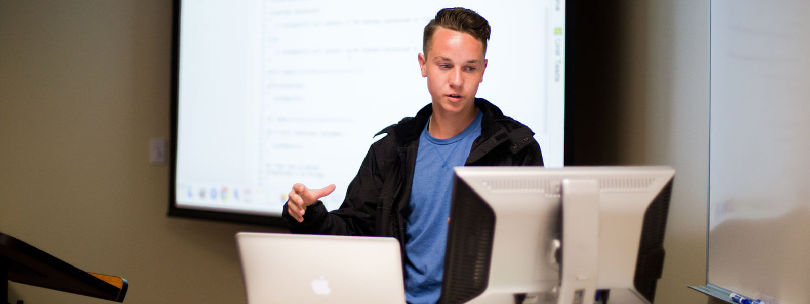student looks at computer screen while giving class presentation