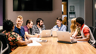 students sit around table working on group project
