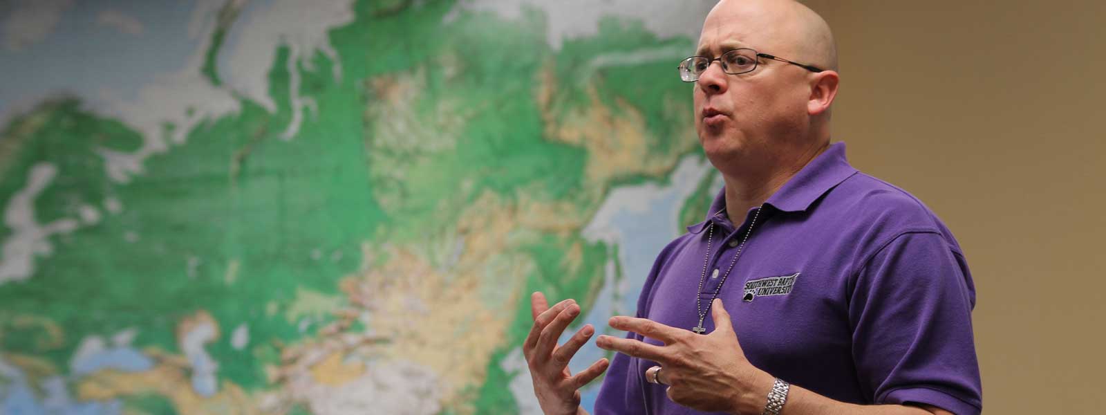 professor lectures in front of large wall map