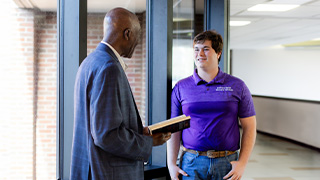 student giving presentation next to map on computer screen