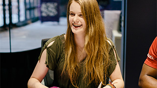 three male students talk to each other while looking at laptop screen