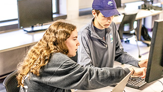 students looking at laptop screens while sitting around conference table