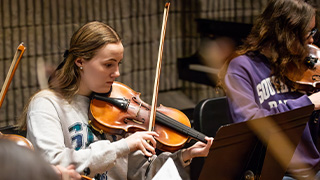 Instrumental and choral ensembles perform on stage together