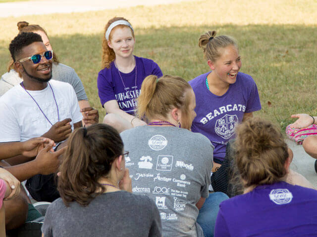 SBU students sitting outside laughing and talking