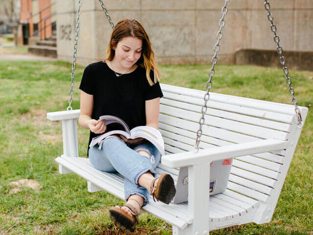 Female student reading on porch swing