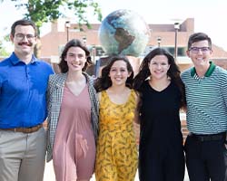 Rocky, Natasha, Christina, Alexis and Jacob stand with arms around each other in front of globe water sculpture