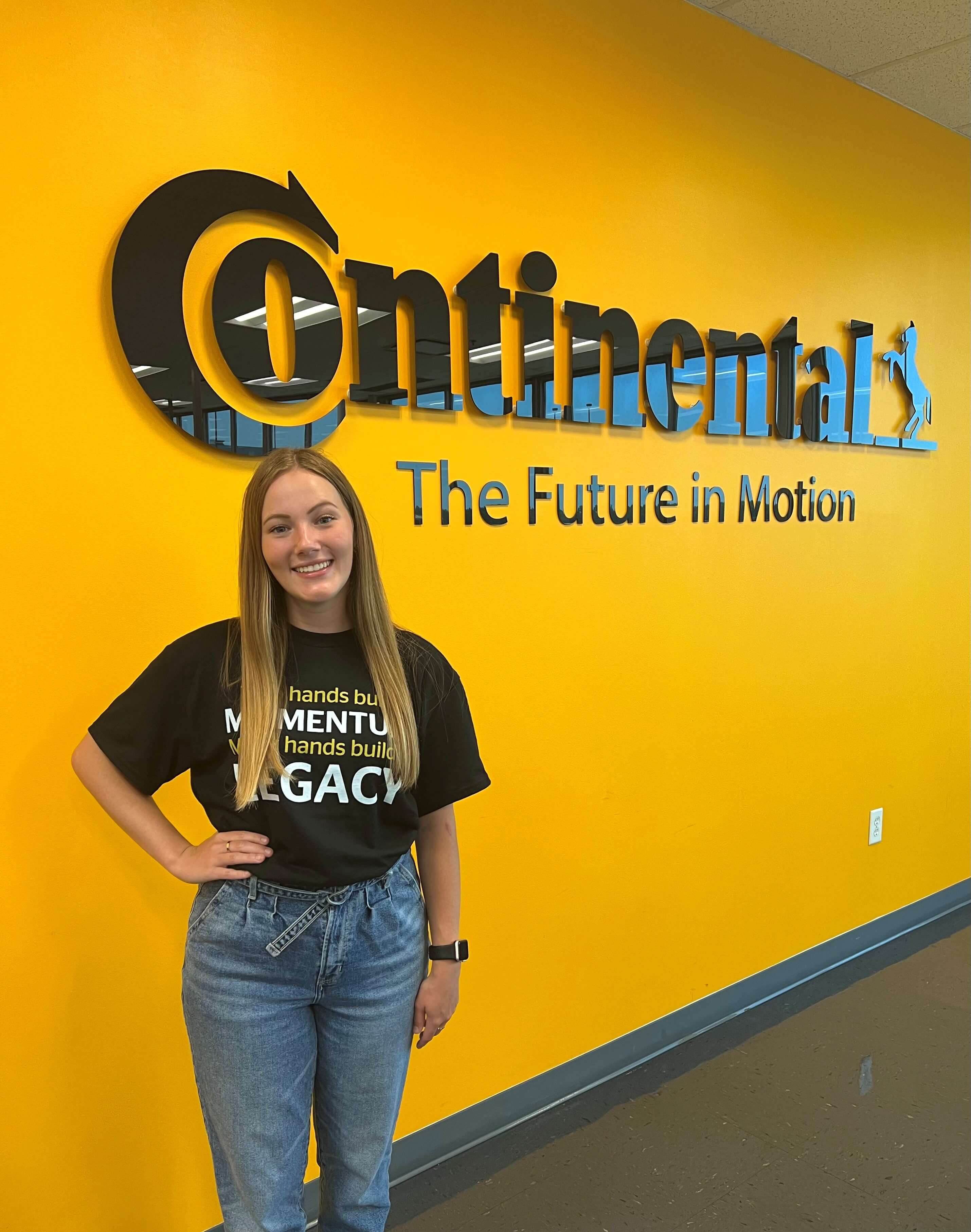 Lauren Berry standing in front of yellow wall with Continental Tire sign