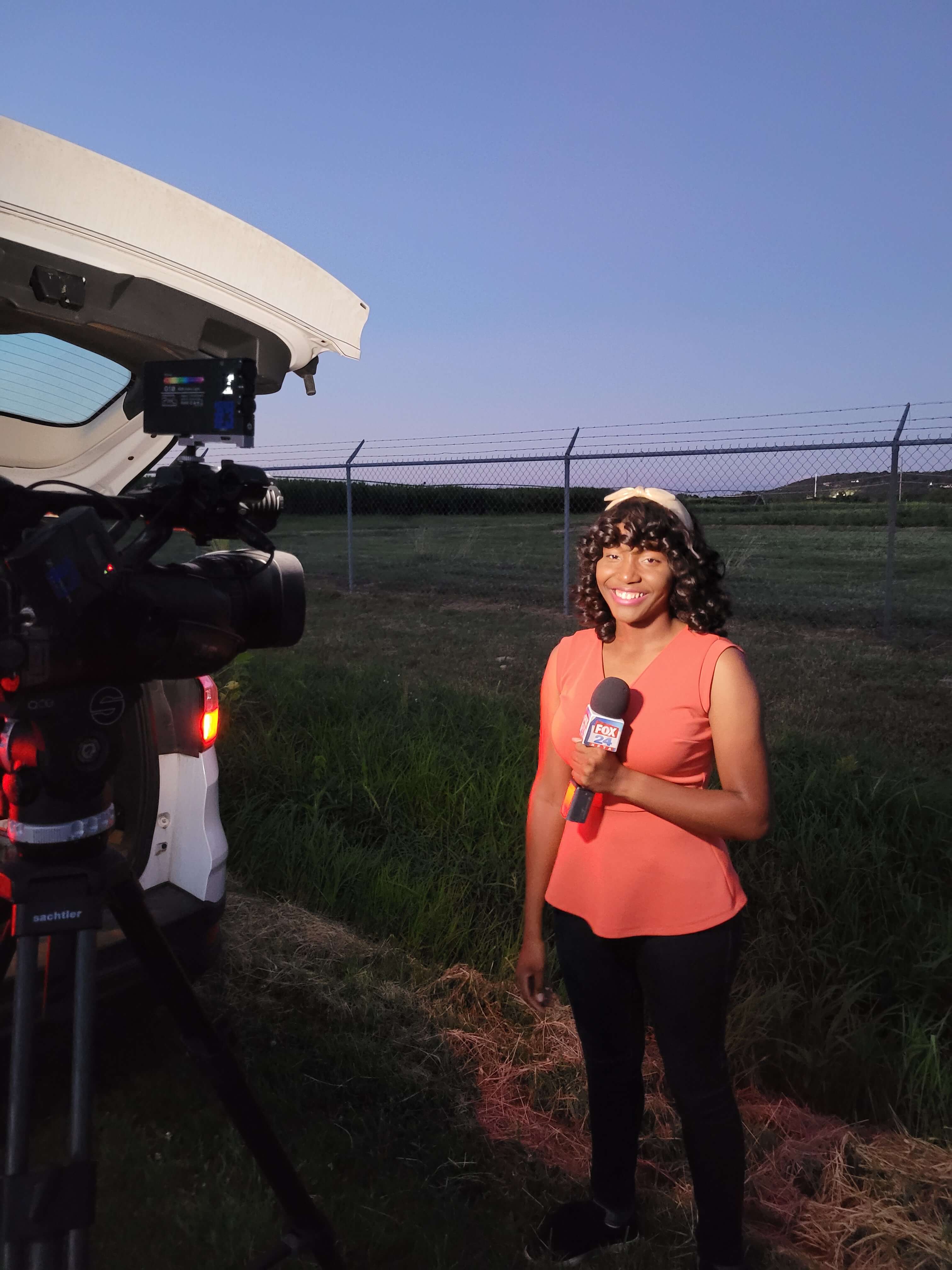 Talya holding microphone and smiling at news camera